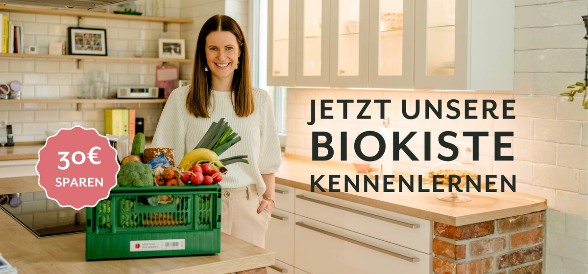 KI generiert: Eine Frau mit Gemüsekiste in der Küche. Text: "JETZT UNSERE BIOKISTE KENNENLERNEN", "30€ SPAREN".