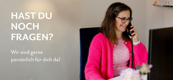 KI generiert: Eine Frau telefoniert lächelnd im Büro. Text: "HAST DU NOCH FRAGEN? Wir sind gerne persönlich für dich da!"